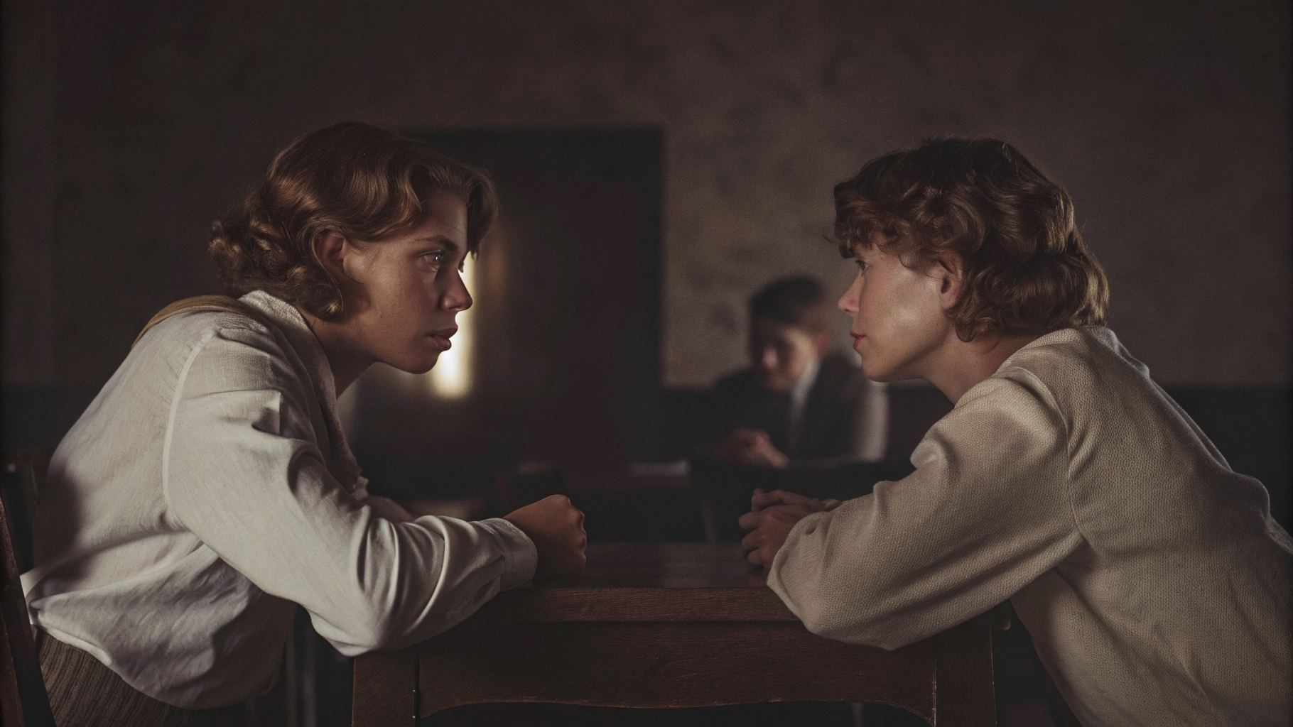 Editorial photograph of two people across a table mid-conversation in warm light
