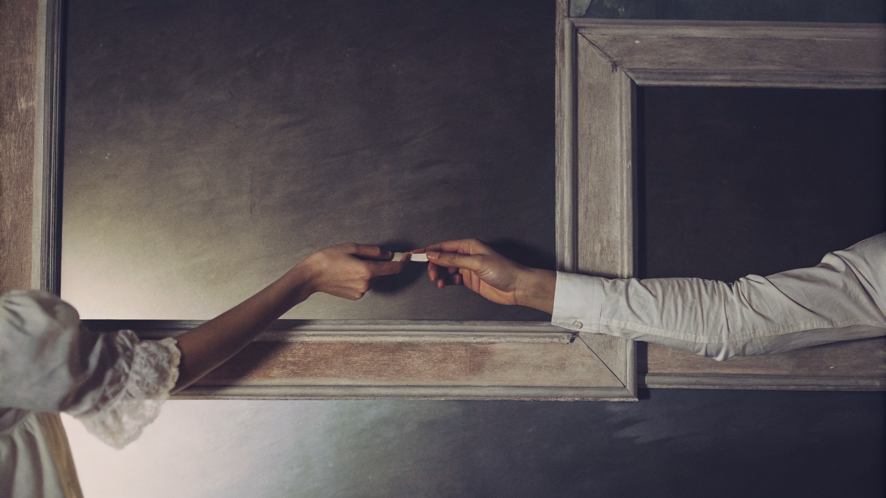 Editorial photograph of a considered handover of a single object between two hands